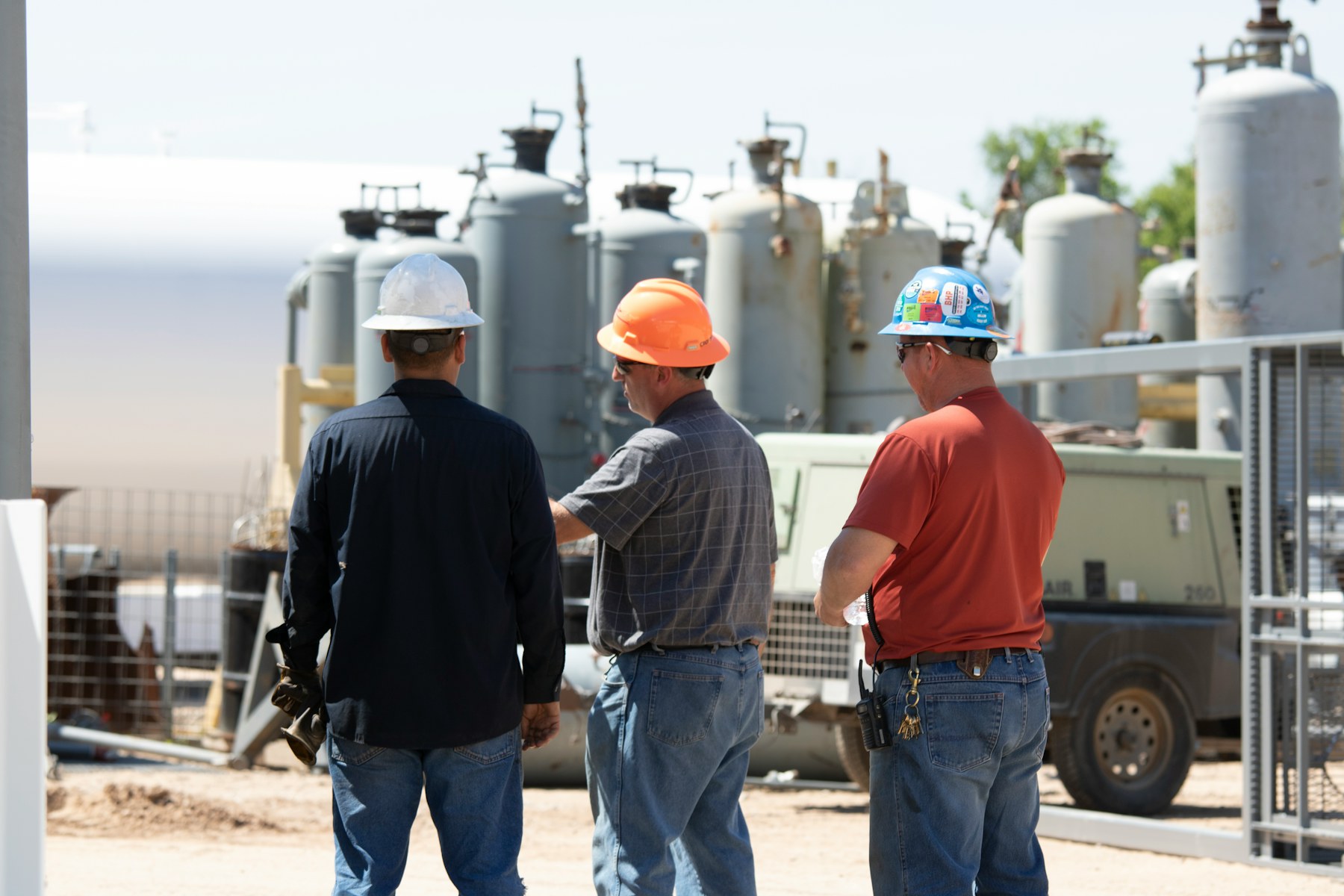 Industrial team discussing equipment while wearing safety helmets